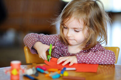 Ilustrační obrázek - holčička stříhající barevný papír. Zdroj: Canva.com